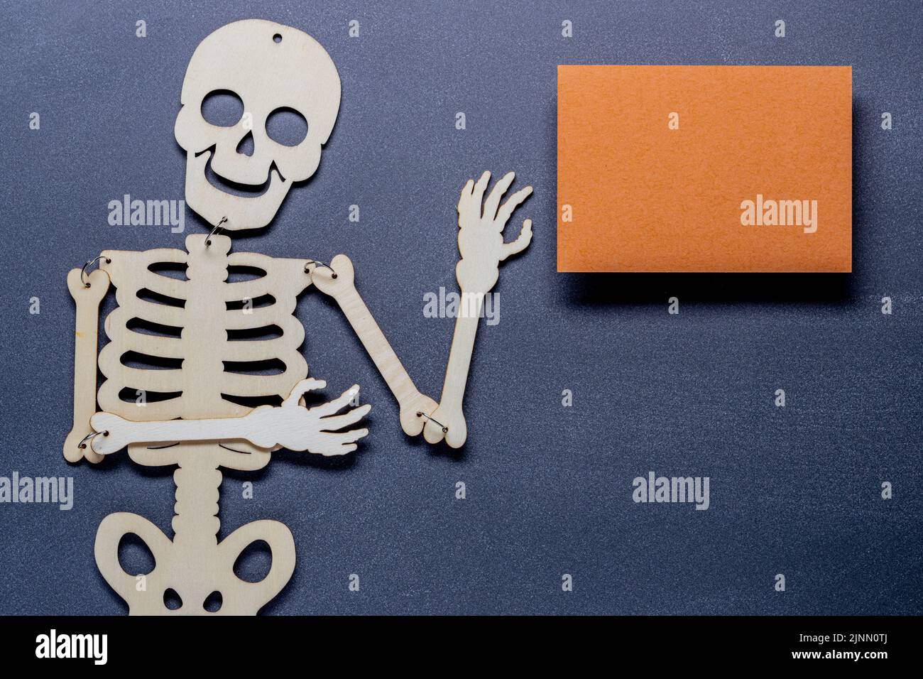 fall or autumn composition of skeleton against a slate blackboard background with an orange paper blank. Flat lay, top view with copy space Stock Photo