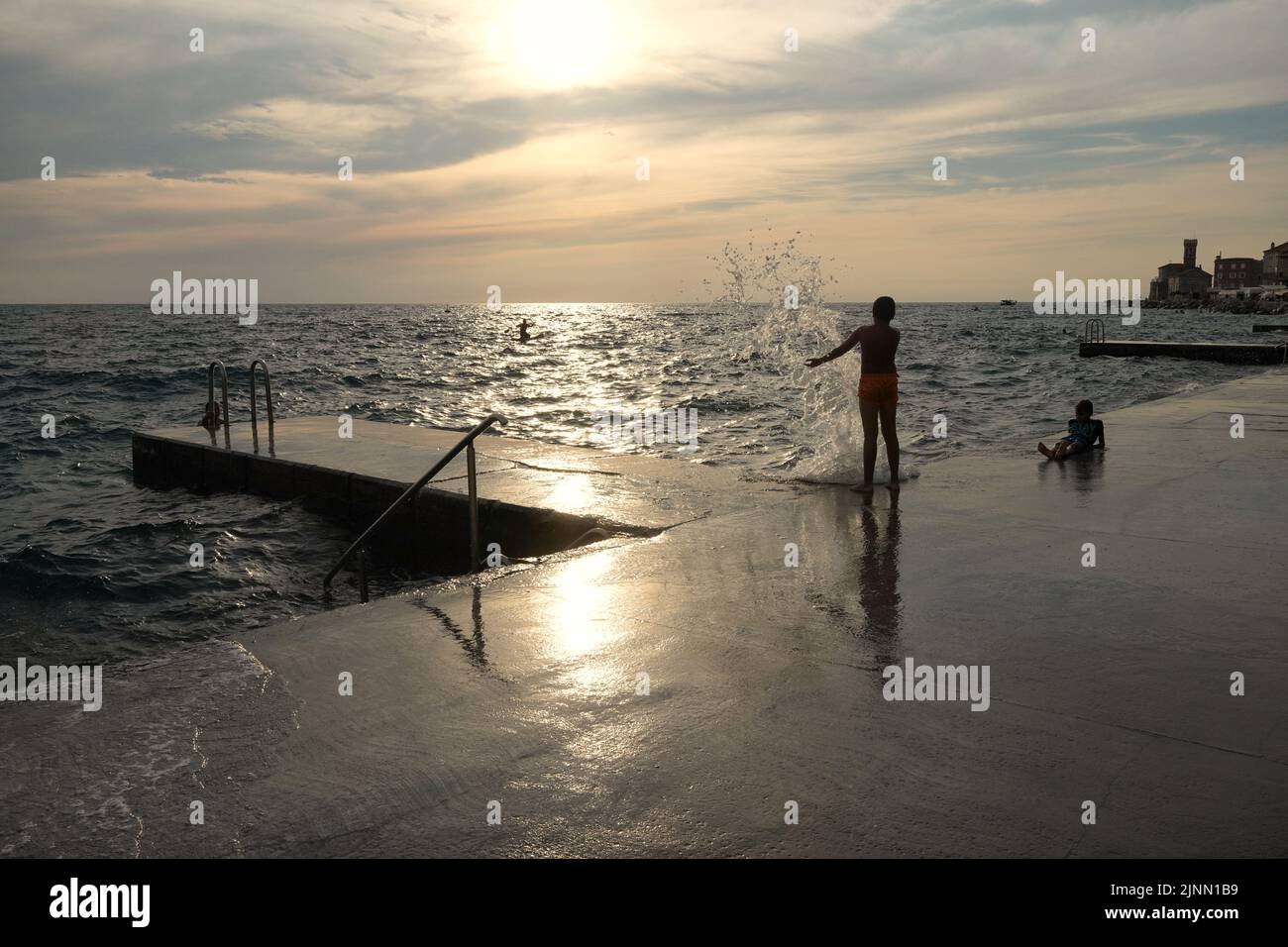 Kids playing with the waves in Piran on the slovenian coast Stock Photo