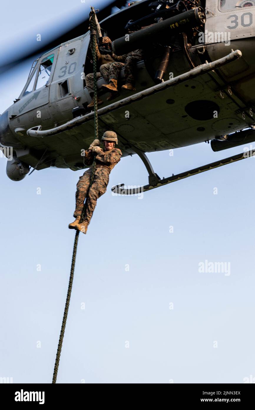 U.S. Marines with Marine Wing Support Squadron (MWSS) 171 fast rope out of a UH-1Y Venom assigned to Marine Light Attack Helicopter Squadron (HMLA) 469 during a Fast Rope Masters Course (FRMC) at Landing Zone Sterling, Okinawa, Japan, July 26, 2022. Fast roping allows Marines to enter landing zones that are too dangerous for helicopters to safely land. Fast Rope and Helicopter Rope Suspension Training teaches Marines proper knots and rappelling techniques, and builds confidence for maneuvering from air to ground. (U.S. Marine Corps photo by Pfc. Justin J. Marty) Stock Photo