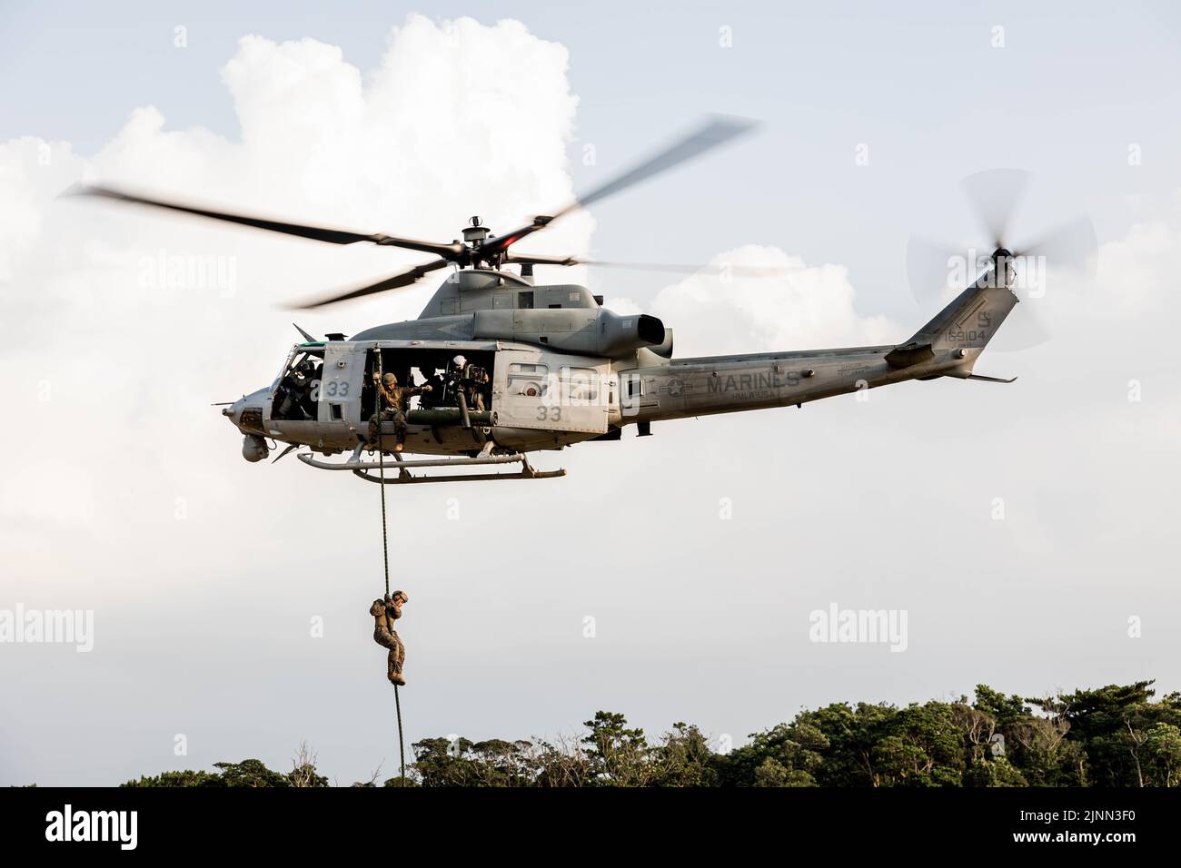 U.S. Marines with Marine Wing Support Squadron (MWSS) 171 fast rope out of a UH-1Y Venom assigned to Marine Light Attack Helicopter Squadron (HMLA) 469 during a Fast Rope Masters Course (FRMC) at Landing Zone Sterling, Okinawa, Japan, July 27, 2022. Fast roping allows Marines to enter landing zones that are too dangerous for helicopters to safely land. Fast Rope and Helicopter Rope Suspension Training teaches Marines proper knots and rappelling techniques, and builds confidence for maneuvering from air to ground. (U.S. Marine Corps photo by Pfc. Justin J. Marty) Stock Photo