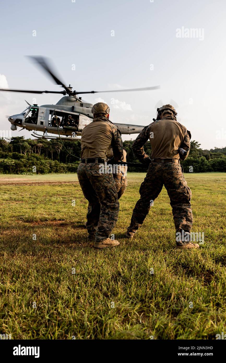 U.S. Marines with Marine Wing Support Squadron (MWSS) 171 pull a rope from a UH-1Y Venom assigned to Marine Light Attack Helicopter Squadron (HMLA) 469 during a Fast Rope Masters Course (FRMC) at Landing Zone Sterling, Okinawa, Japan, July 27, 2022. Fast roping allows Marines to enter landing zones that are too dangerous for helicopters to safely land. Fast Rope and Helicopter Rope Suspension Training teaches Marines proper knots and rappelling techniques, and builds confidence for maneuvering from air to ground. (U.S. Marine Corps photo by Pfc. Justin J. Marty) Stock Photo