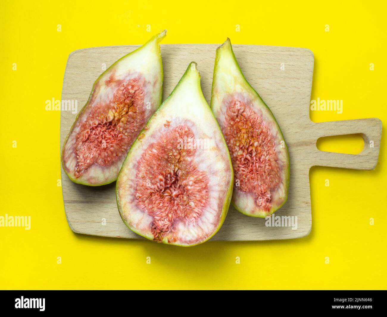 sliced figs on a cutting board. Juicy ripe fruit on a yellow background. Diet food. Fig isolate. Seeds inside. Bright picture. fruit concept Stock Photo