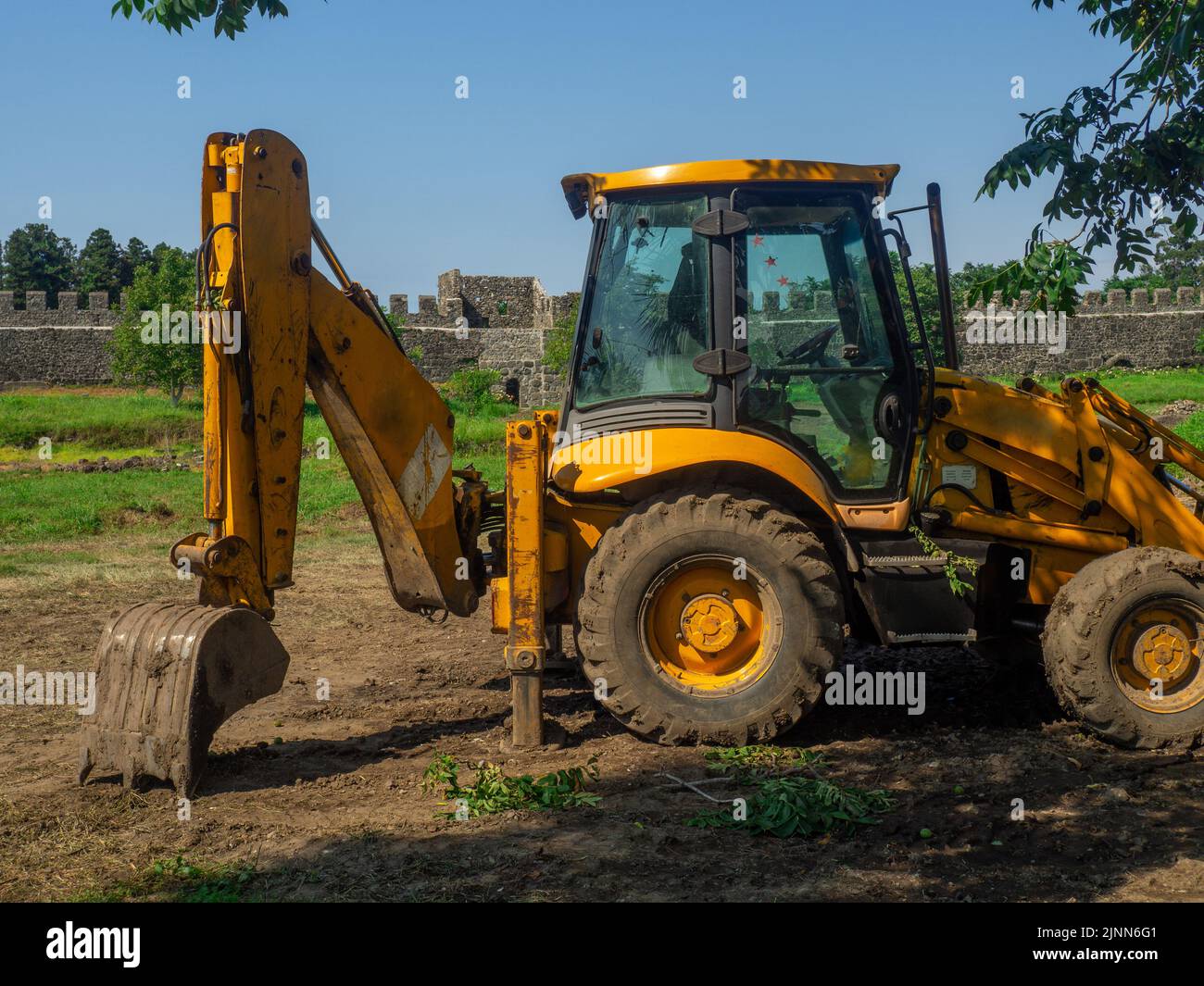 A tractor with a bucket is standing next to the working area. Tractor