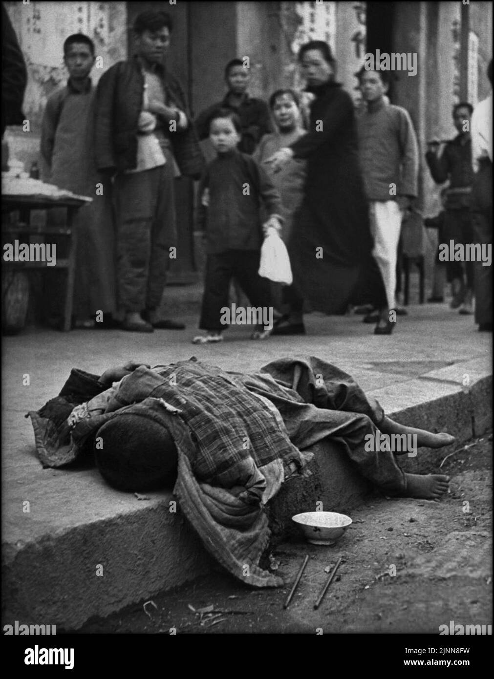 A harrowing image taken by George Silk, an abandoned child lying dying in thestreet while crowd looks on. The image was taken during the famine in China in 1946 Stock Photo