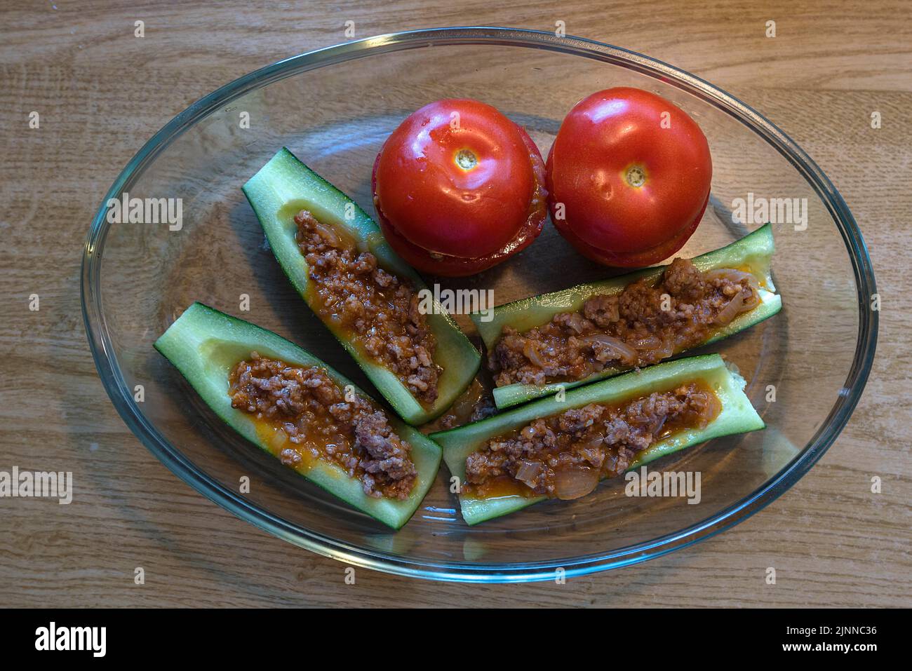 Stuffed peppers and tomatoes in a glass casserole on a wooden table, Bavaria, Germany Stock Photo