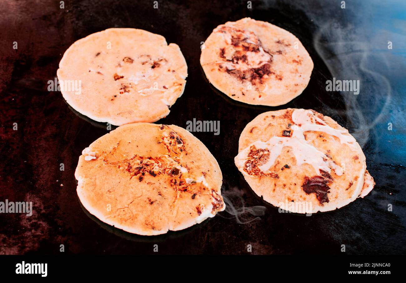 Traditional grilled cheese pupusas, Top view of four traditional handmade pupusas on grill. Traditional Salvadoran pupusas with melted cheese on a Stock Photo