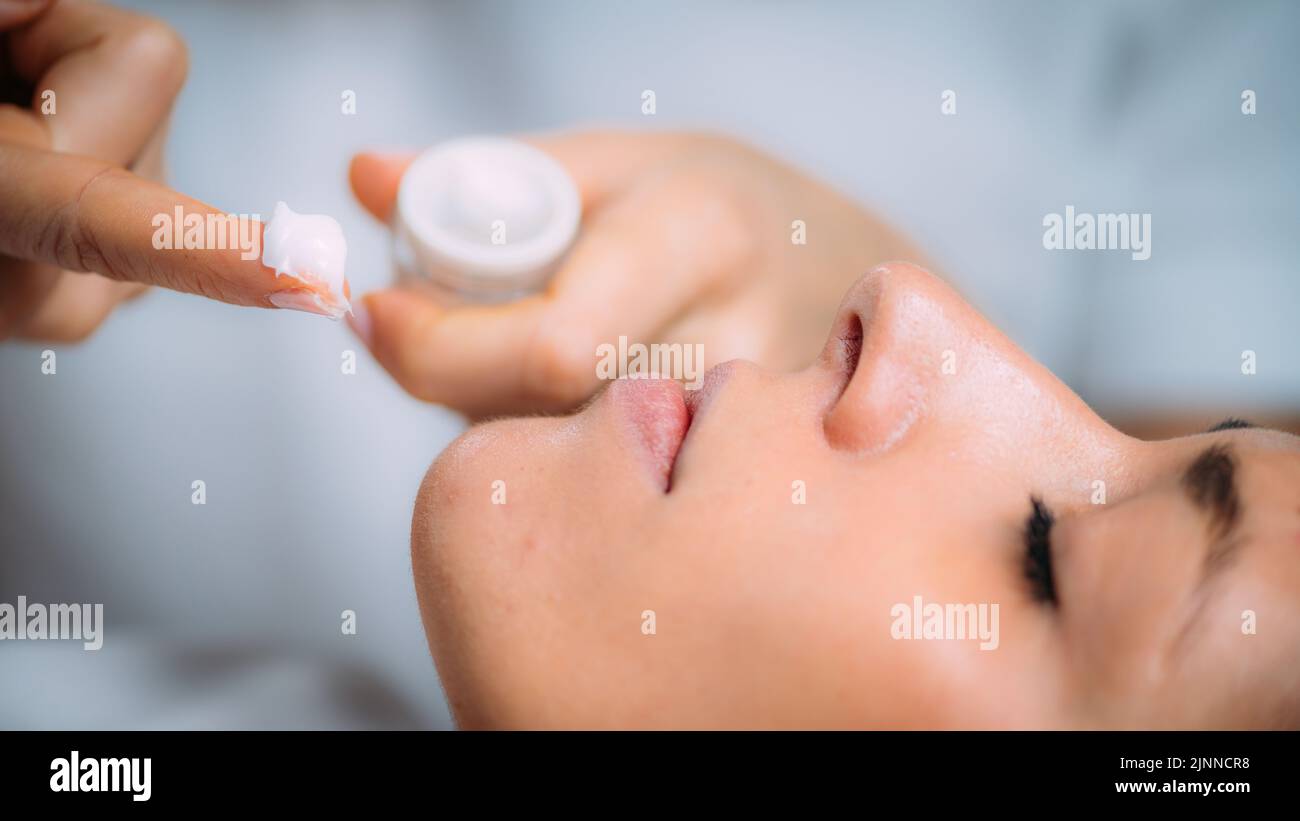 Cosmetician applying cream to face Stock Photo
