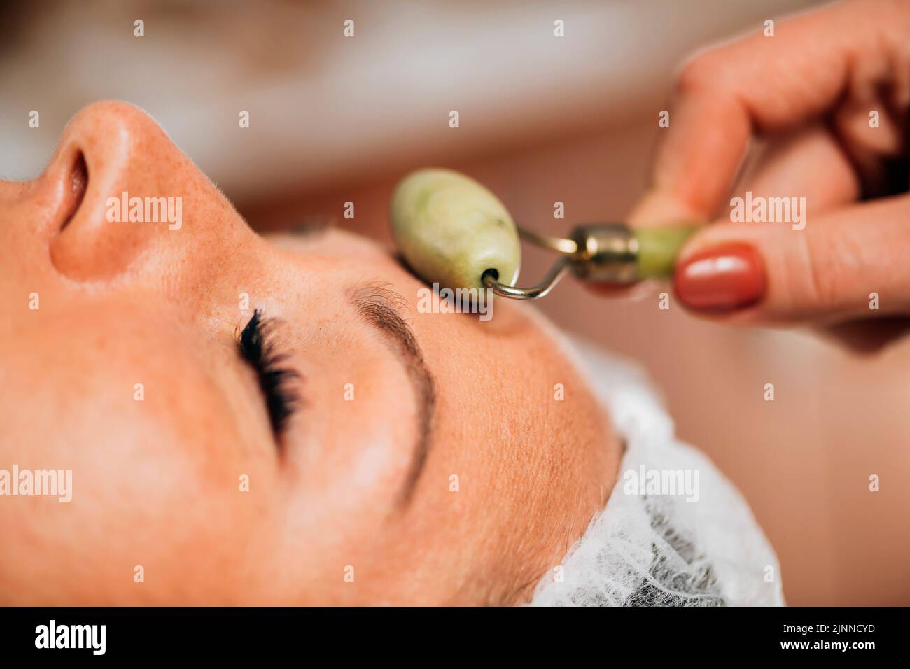 Anti-aging face massage with jade roller Stock Photo