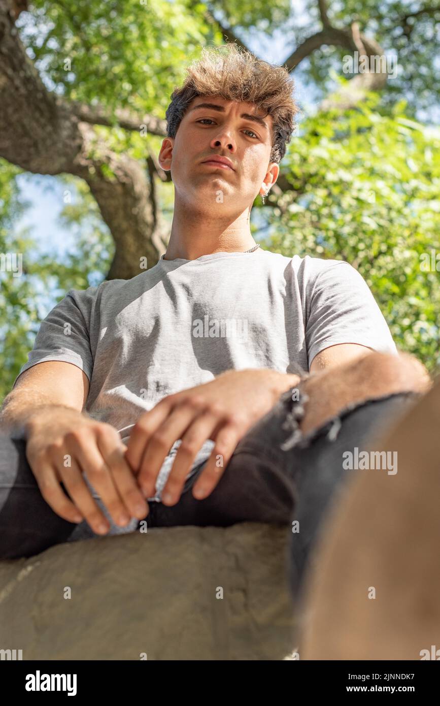 Low angle of a young man, serious, looking at the camera in a public park Stock Photo