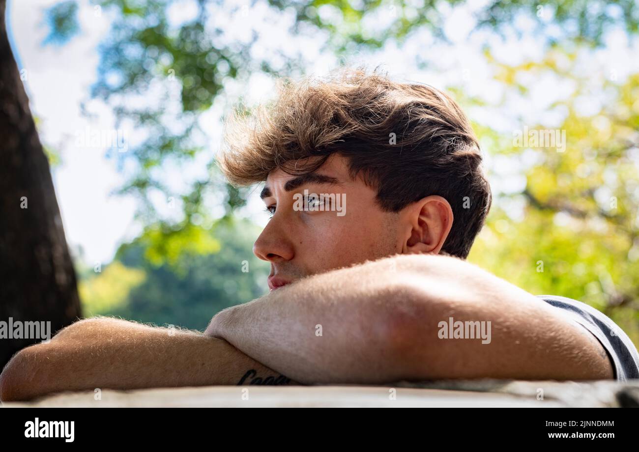 Young man falls his head down on his arms, in a public park Stock Photo