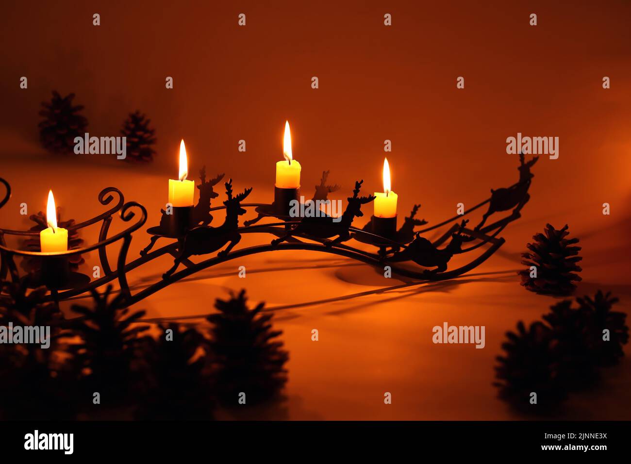 Fourth Advent with four lit candles on a sleigh with reindeer in