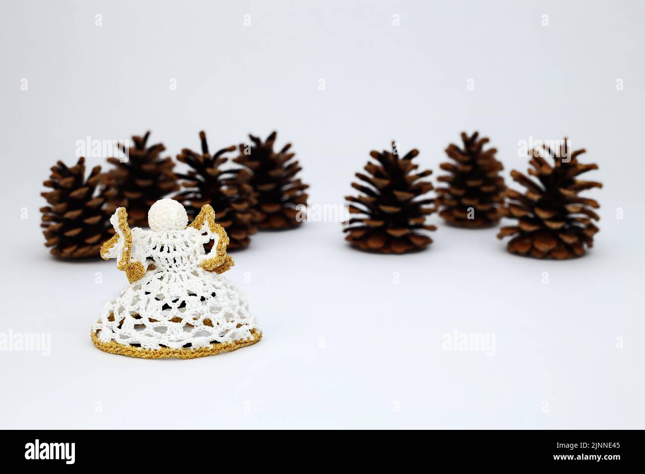 Crochet angel and pine cone or pine cone crocheted against a white background with a sharpening gradient Stock Photo