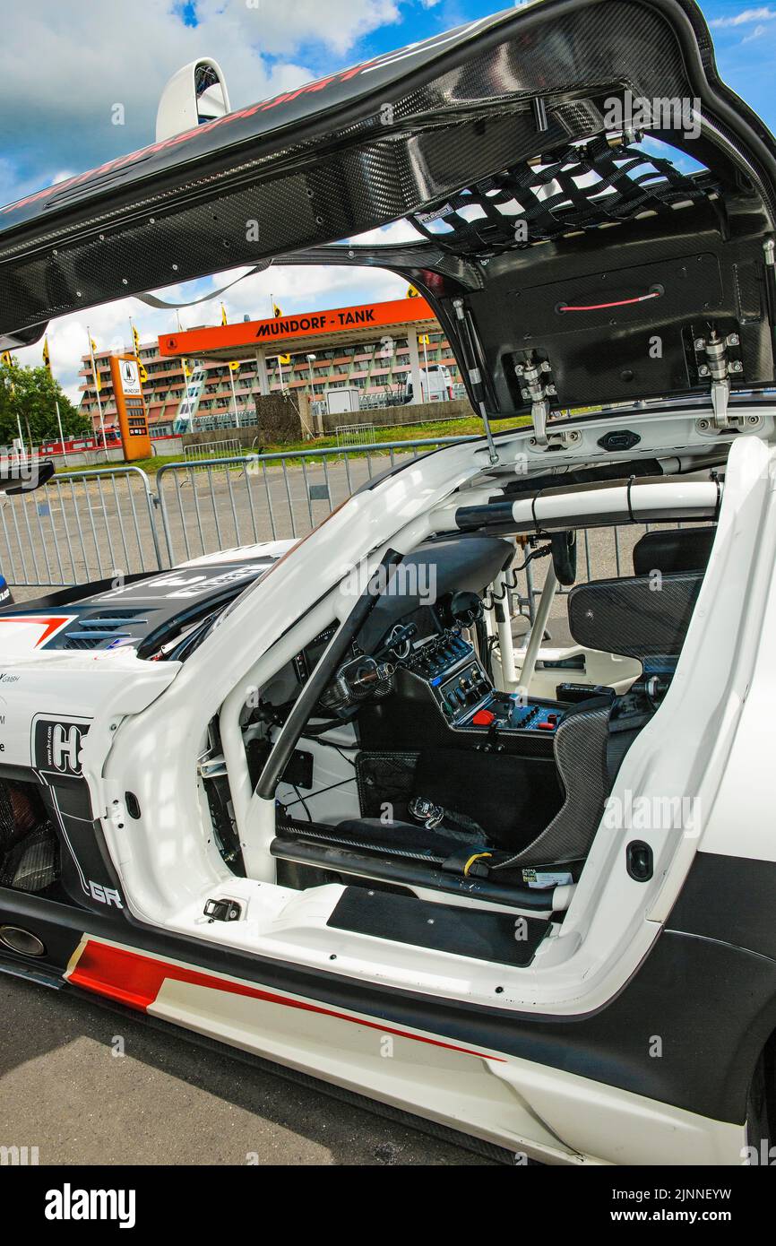 View into interior cockpit of racing car Mercedes-AMG GT3 with bucket seat centre console electronic controls, gullwing doors open on top Stock Photo