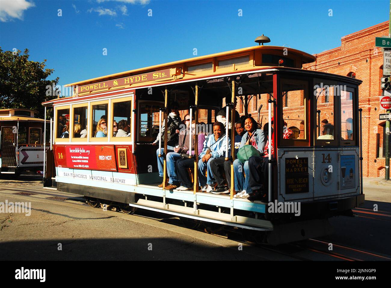 Tourists take a seat and ride the cable car through the streets of San ...
