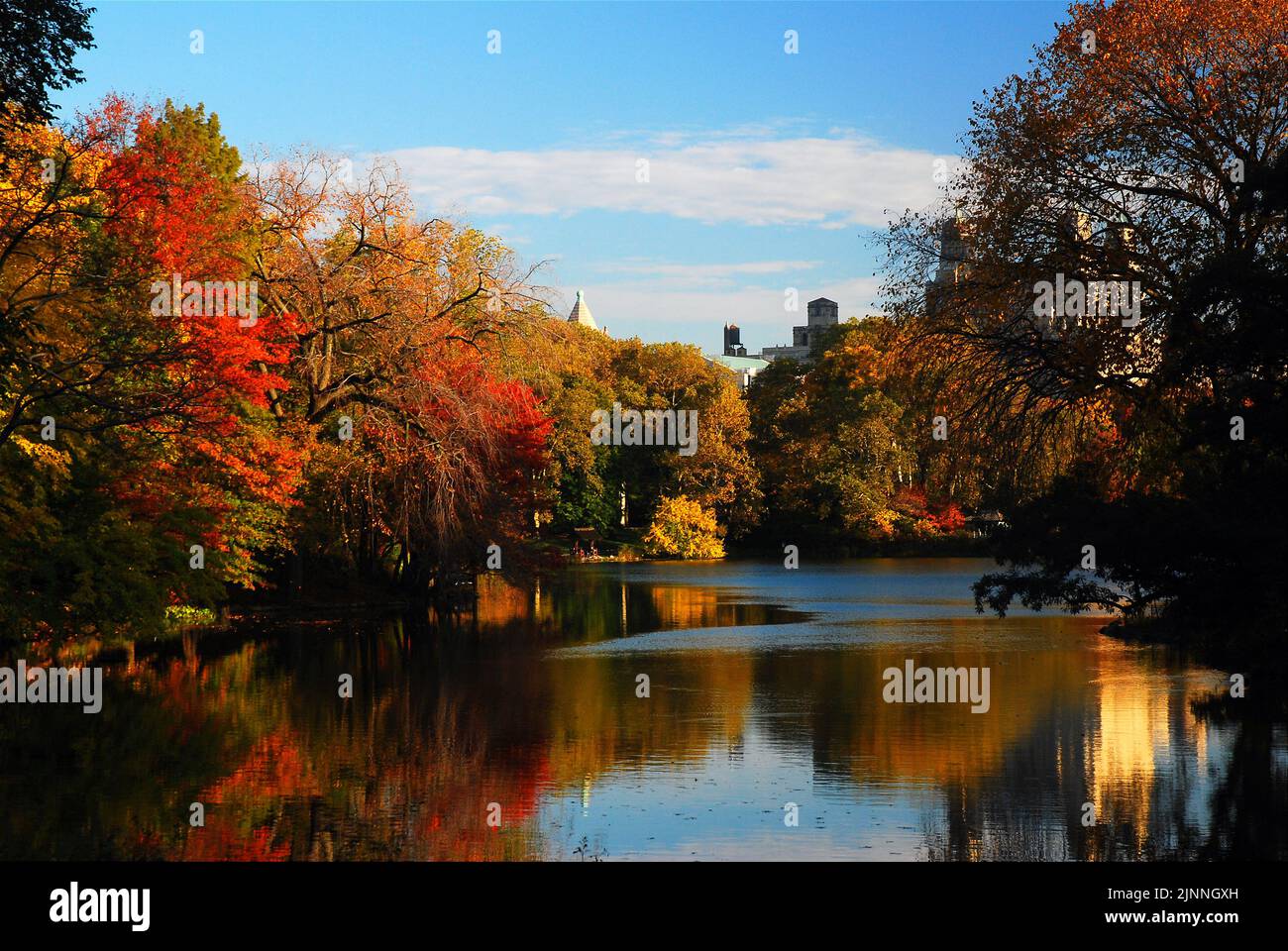 The autumn colors and fall foliage are reflected in the calm waters of the lake in New York's Central park on a crisp sunny day Stock Photo