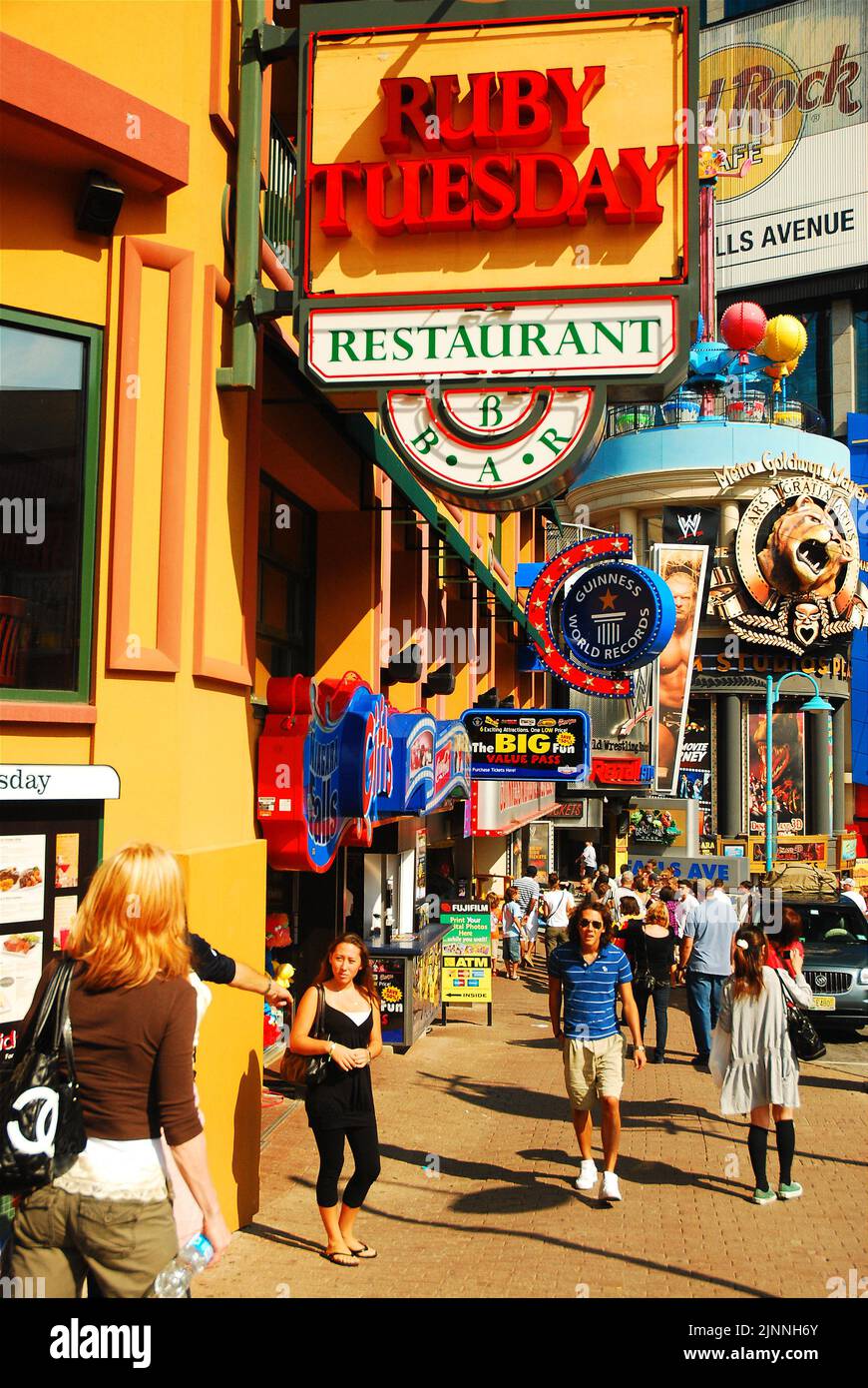 Tourists walk along the main business street of Clifton Hill in Nagara Falls, Ontario, passing tacky souvenir shops and a plethora of fast food cafes Stock Photo