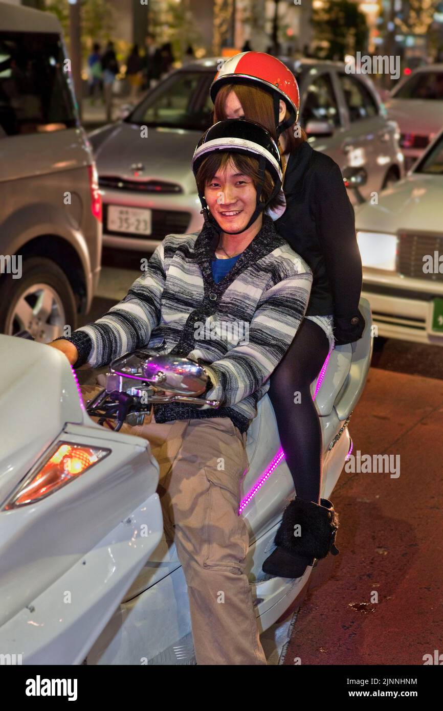 Young couple on motor scooter night Shinjuku Tokyo Japan Stock Photo