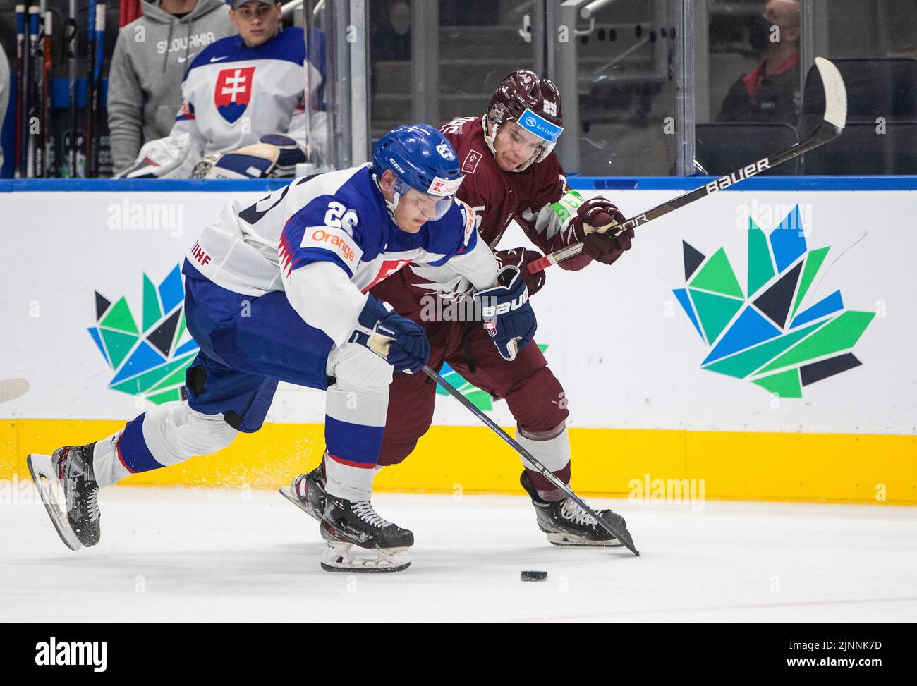 August 12, 2022, EDMONTON, AB, CANADA Slovakias Simon Groch and Latvias Felikss Gavars (25) battle for the puck during third period IIHF World Junior Hockey Championship action in Edmonton on Friday August