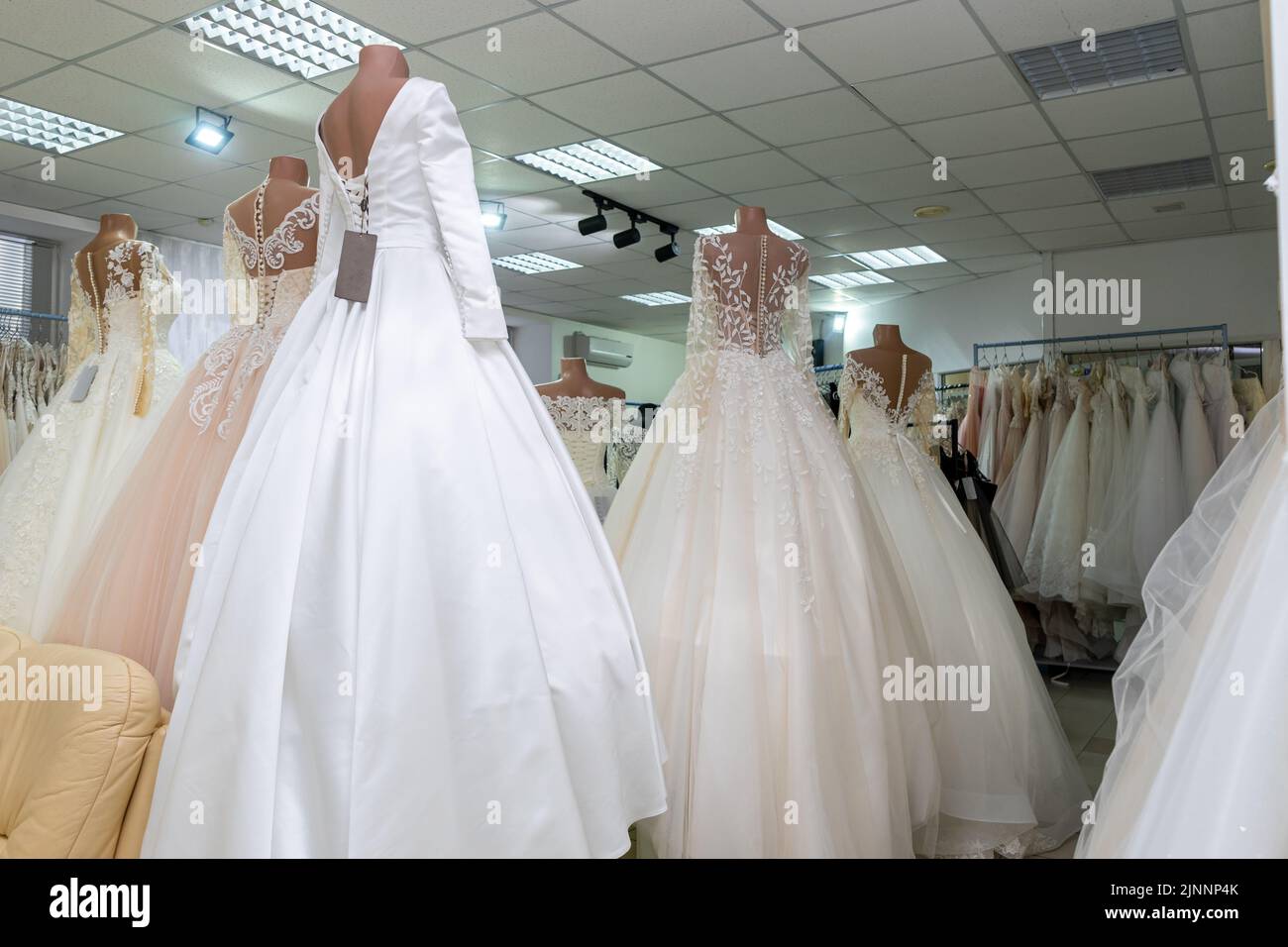 Several wedding dresses on mannequins in a wedding salon. Rear view Stock Photo