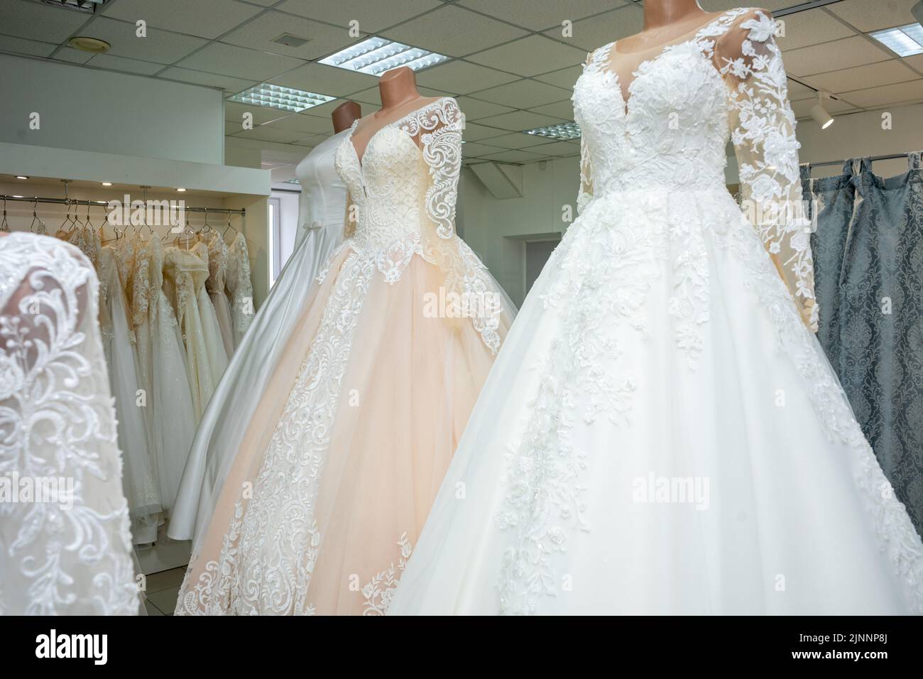 Beautiful wedding dresses in a bridal boutique on mannequins Stock Photo