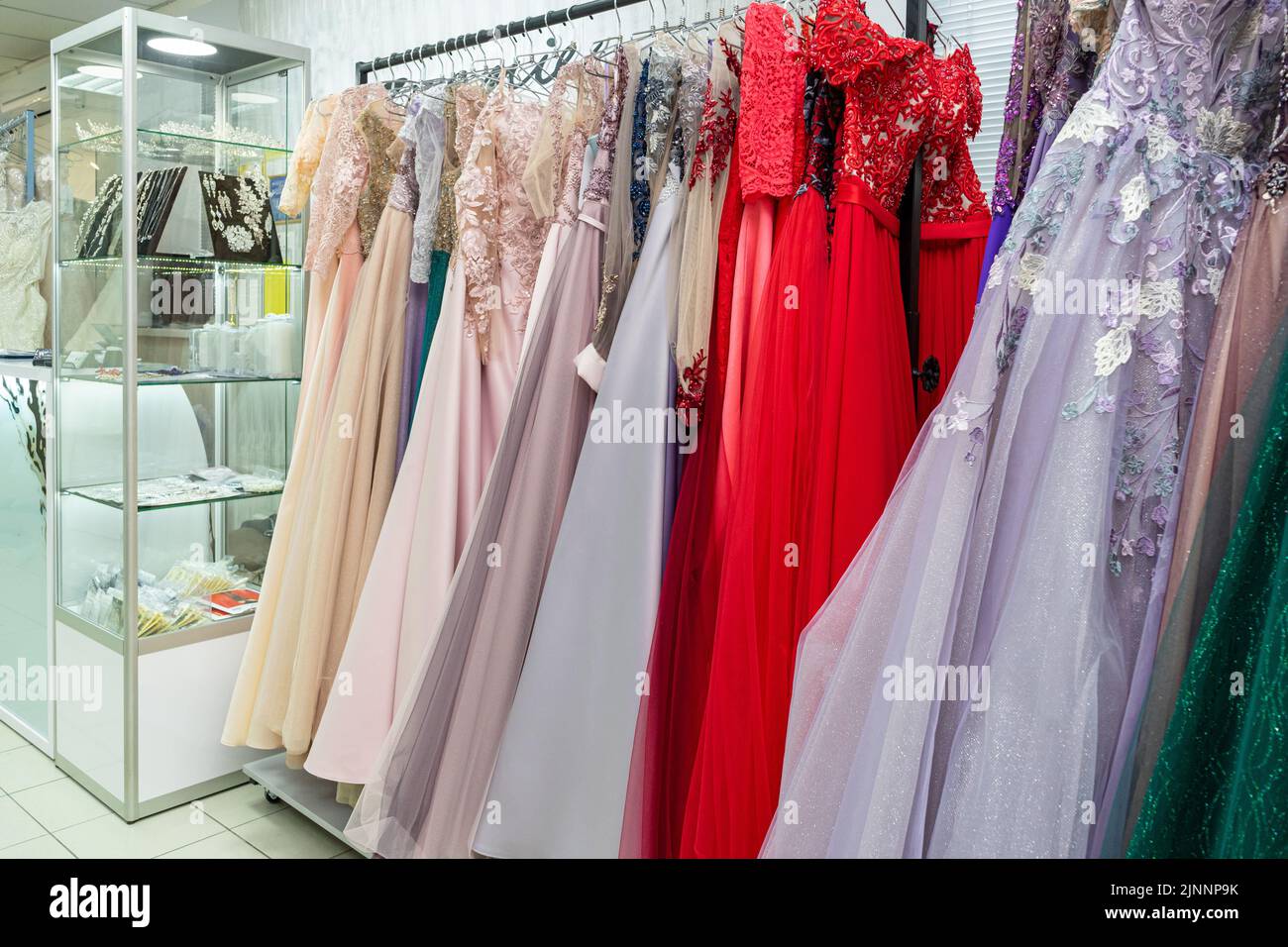Multicolored wedding and evening dresses on a rack in a bridal shop Stock Photo