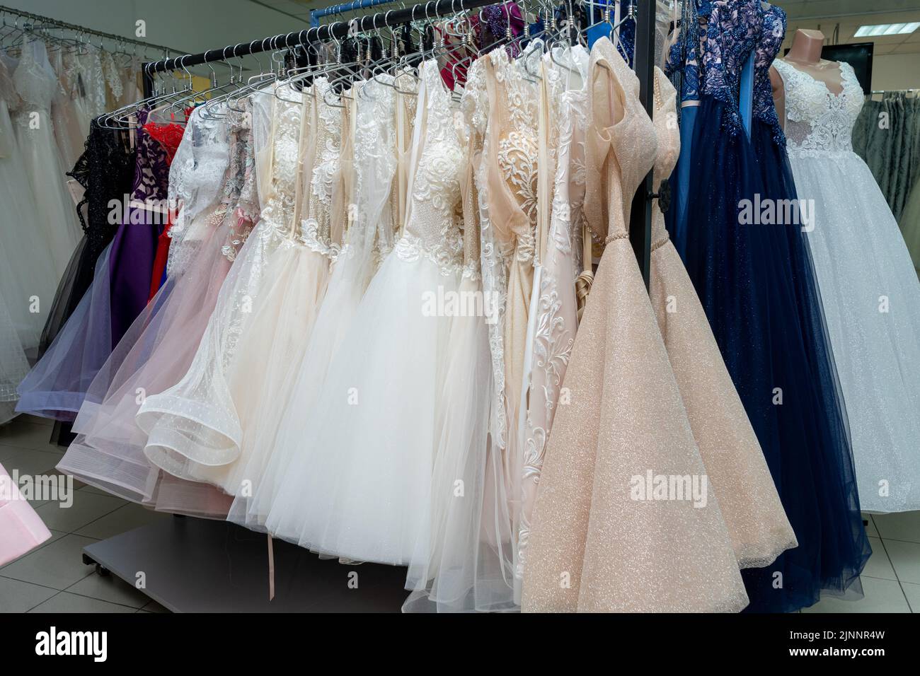 Many different evening dresses and bridal dresses on a hanger in the store Stock Photo