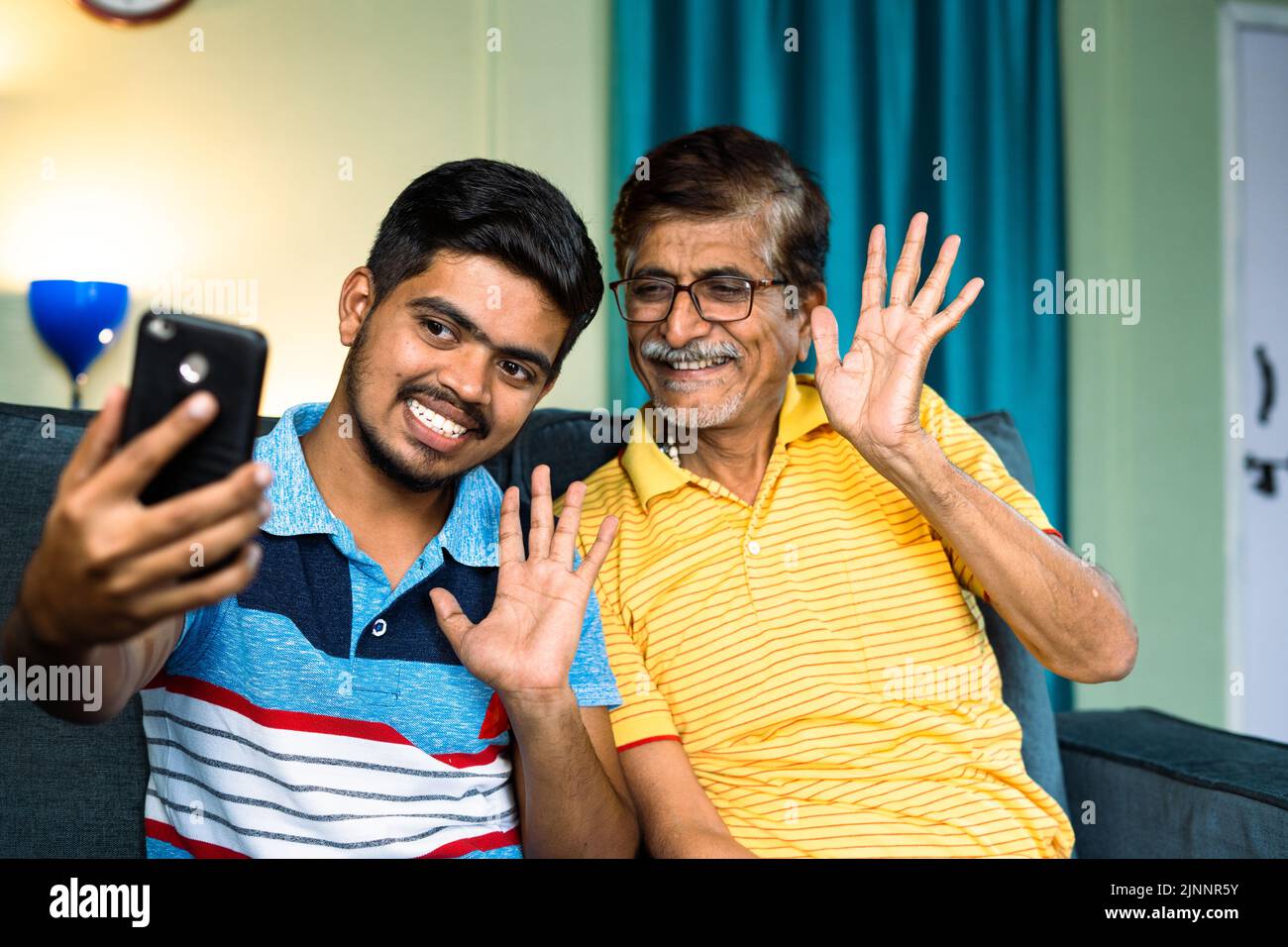 Happy smiling grandfather and grandson making video call on mobile phone at home - concept of family connection or bonding and technology and positive Stock Photo