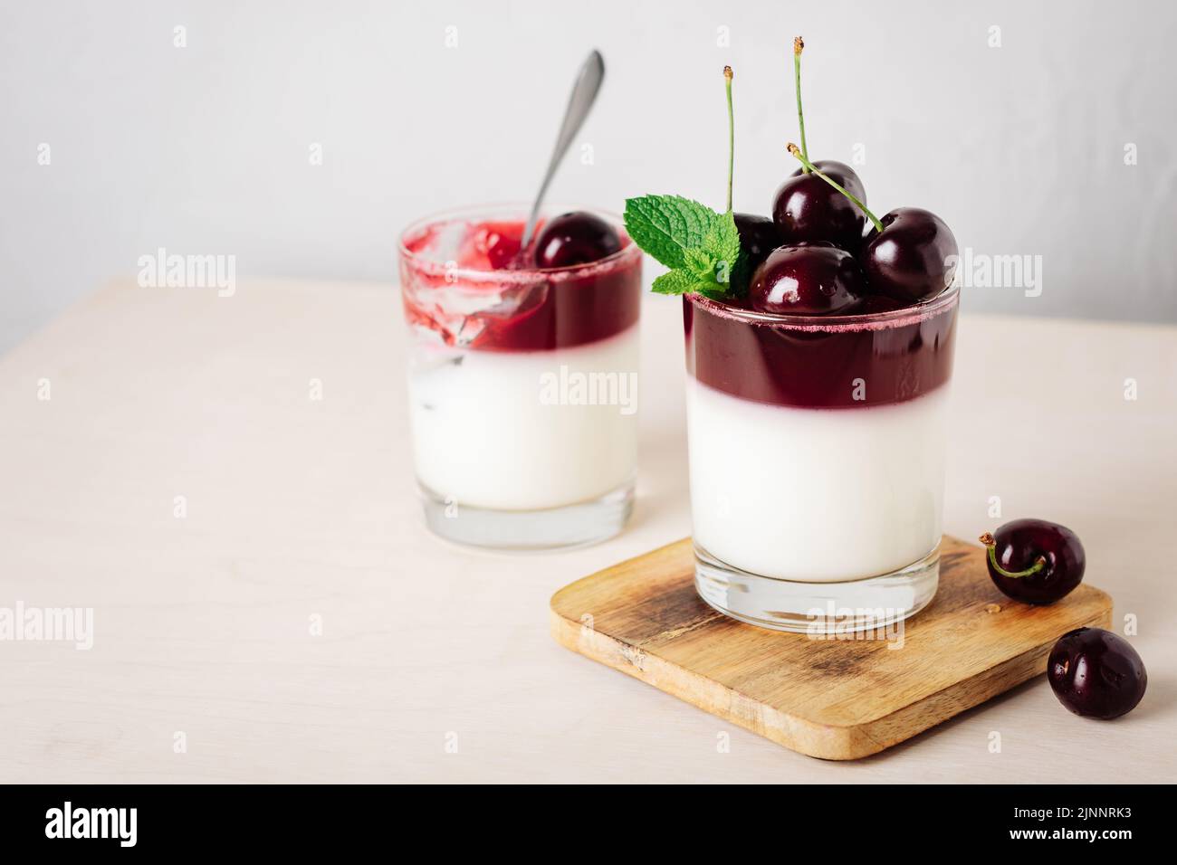 Gelatin dessert. Yoghurt and cherry jelly on a light background Stock