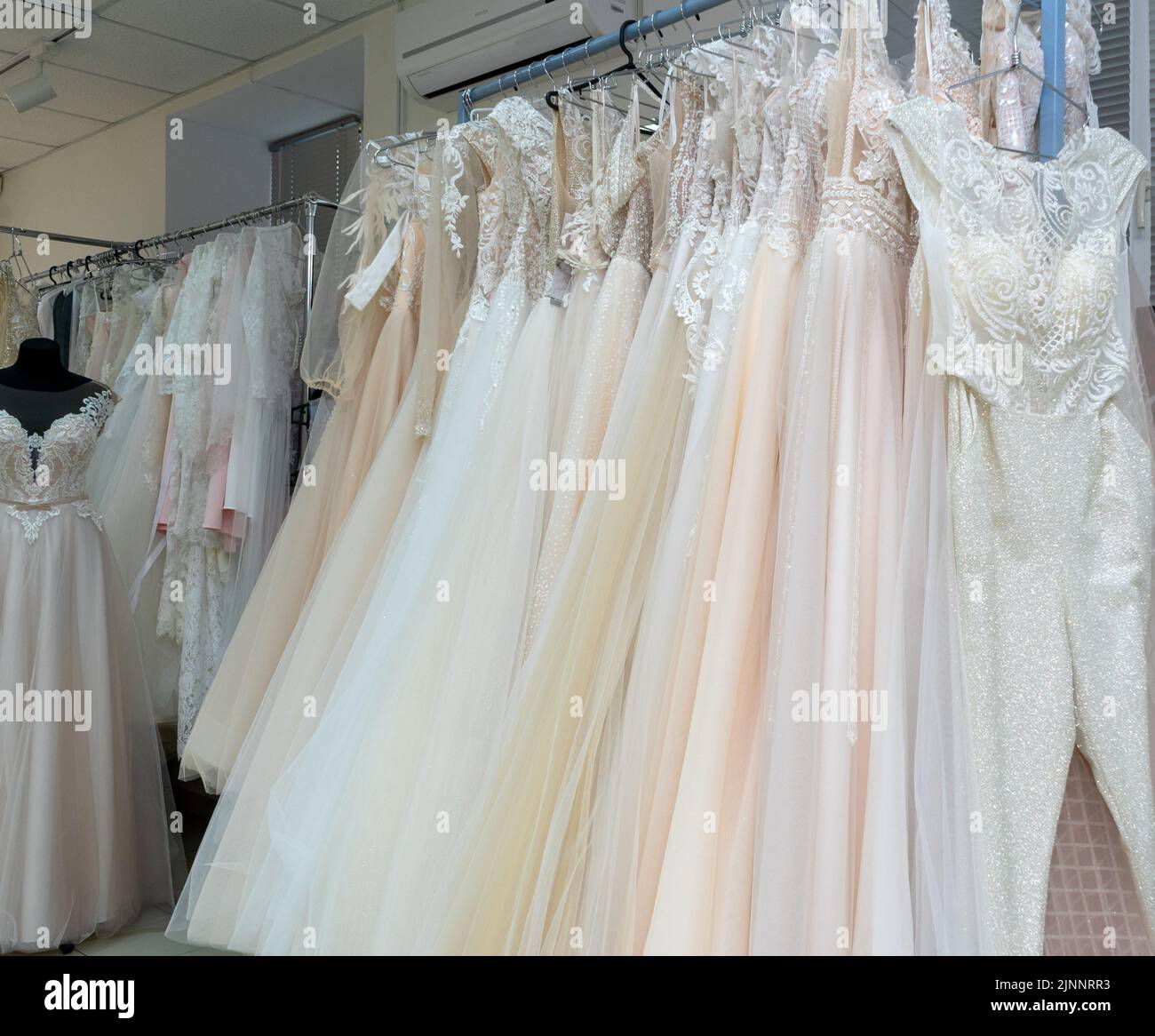 White and cream wedding dresses on a hanger in a bridal boutique. Close up Stock Photo