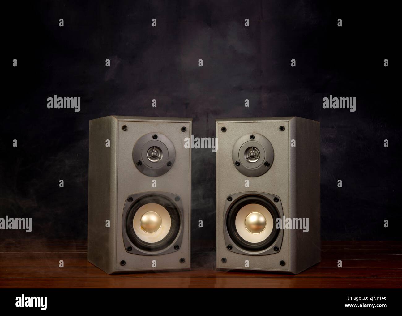 Two audio speakers with smoke in dark background room. Stock Photo