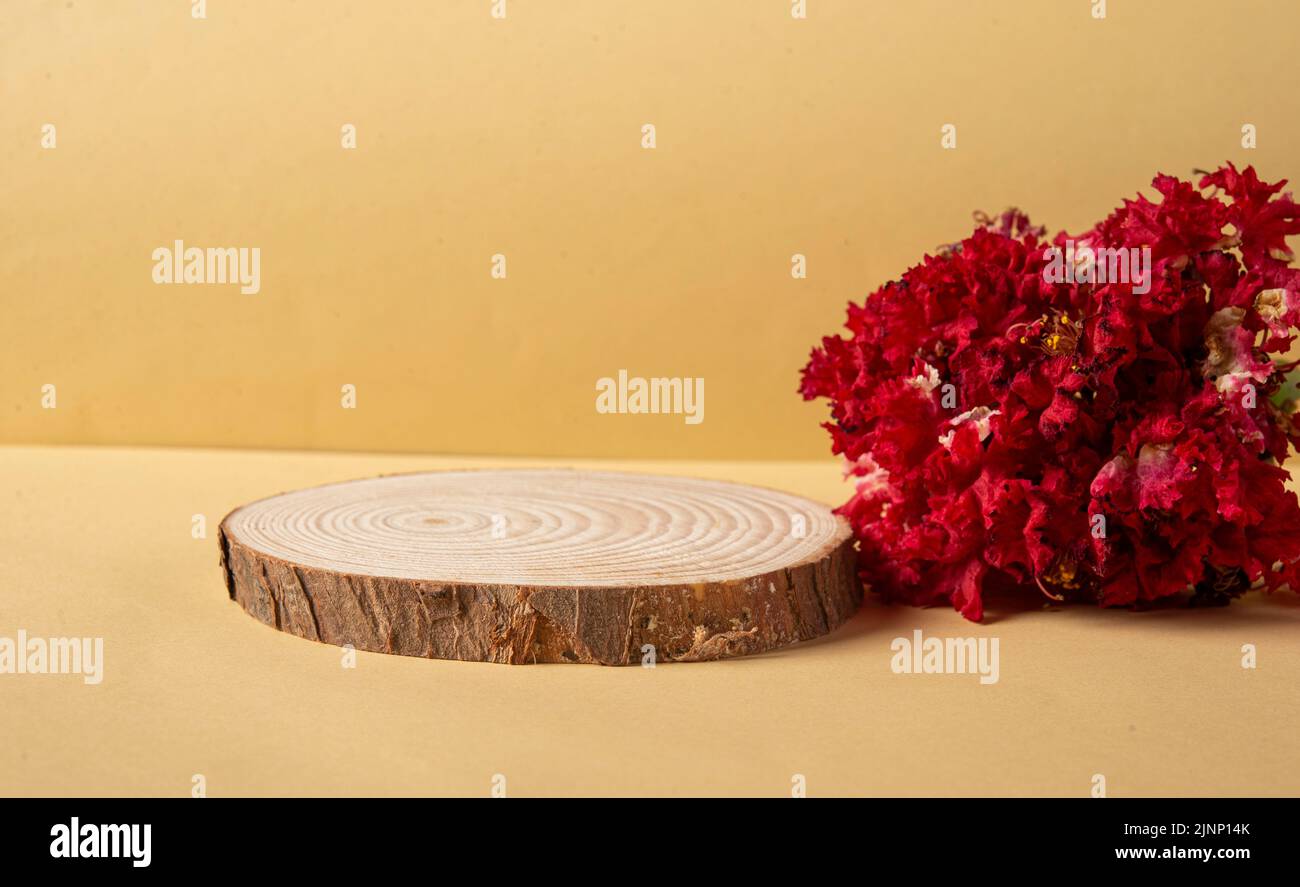Wooden podium with red natural flowers and product mockup space. Stock Photo