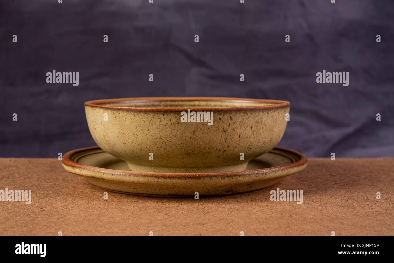 Rustic clay soup bowl closeup view with grey background. Stock Photo