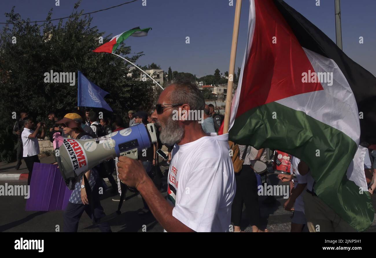 Israeli left-wing activists and Palestinians hold Palestinian flags as they march during a demonstration against Israeli occupation and settlement activity in the Sheikh Jarrah neighborhood on August 12, 2022 in Jerusalem, Israel. The Palestinian neighborhood of Sheikh Jarrah is currently the center of a number of property disputes between Palestinians and right-wing Jewish Israelis. Some houses were occupied by Israeli settlers following a court ruling. Stock Photo