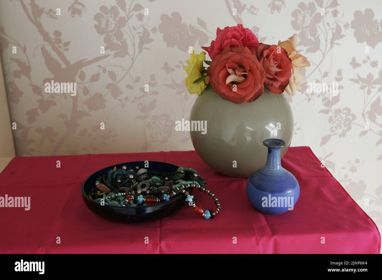 flowers in a Vase and plant pot on dressing table with ornaments Stock