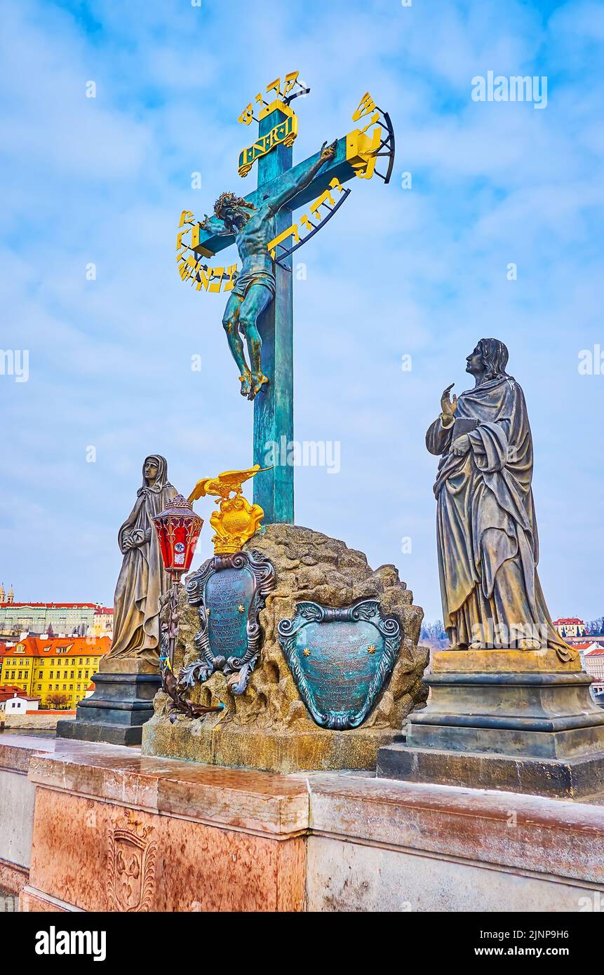 Historic bronze Calvary statue on the Charles Bridge with stone statues on both sides of the Cross, Prague, Czech Republic Stock Photo