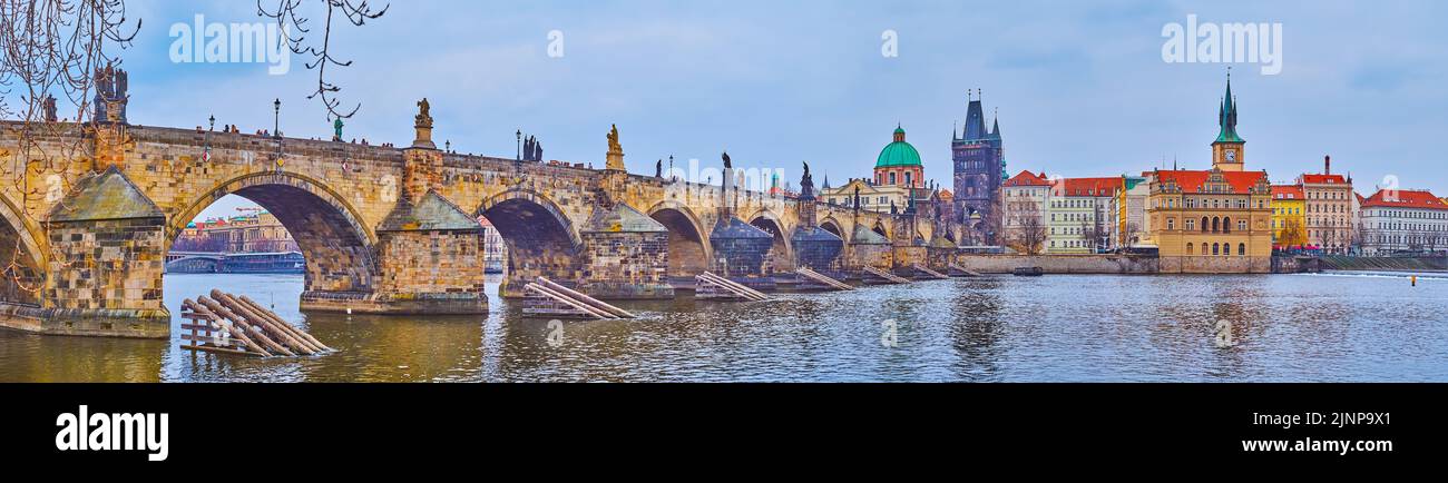 Panorama of Vltava River, arched sculptured stone Charles Bridge with Old Town Bridge Tower, dome of St Franciss of Assisi Church and historic housing Stock Photo