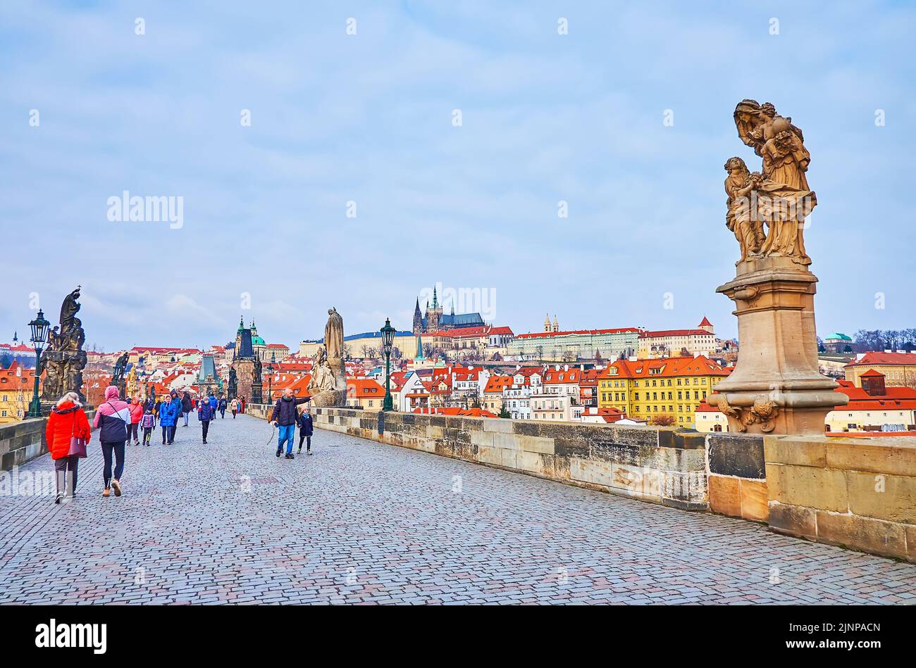 PRAGUE, CZECH REPUBLIC - MARCH 6, 2022:  The carved stone statues on Charles Bridge with St Vitus Cathedral of Prague Castle in the background, on Mar Stock Photo
