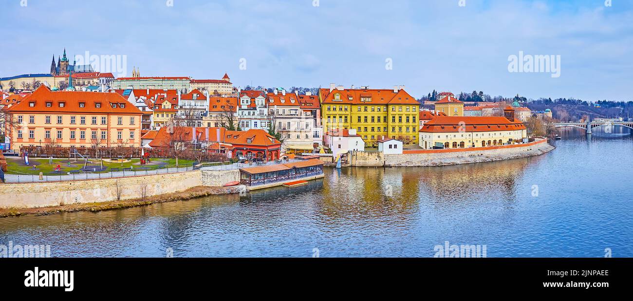 Panorama with rippled waters of Vltava River, red roofs of Mala Strana (Lesser Quarter) and St Vitus Cathedral atop the Castle Hill of Prague Castle, Stock Photo