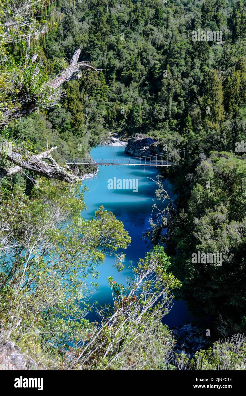 A swing bridge across the turquoise blue Hokitika Gorge, deep in the rain forest near Hokitika on the west coast of South Island in New Zealand Stock Photo