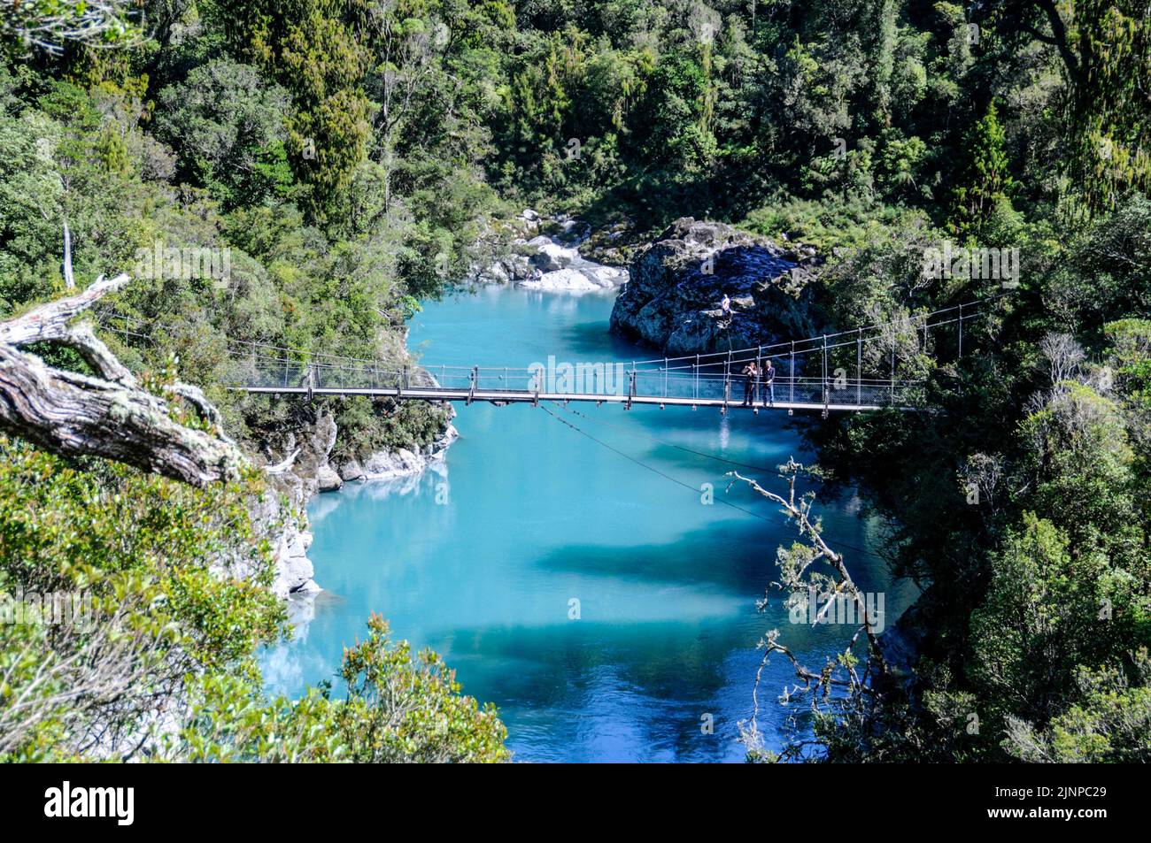 A foot swing bridge across the natural  turquoise blue water at Hokitika Gorge on the west coast of South Island in New Zealand Stock Photo