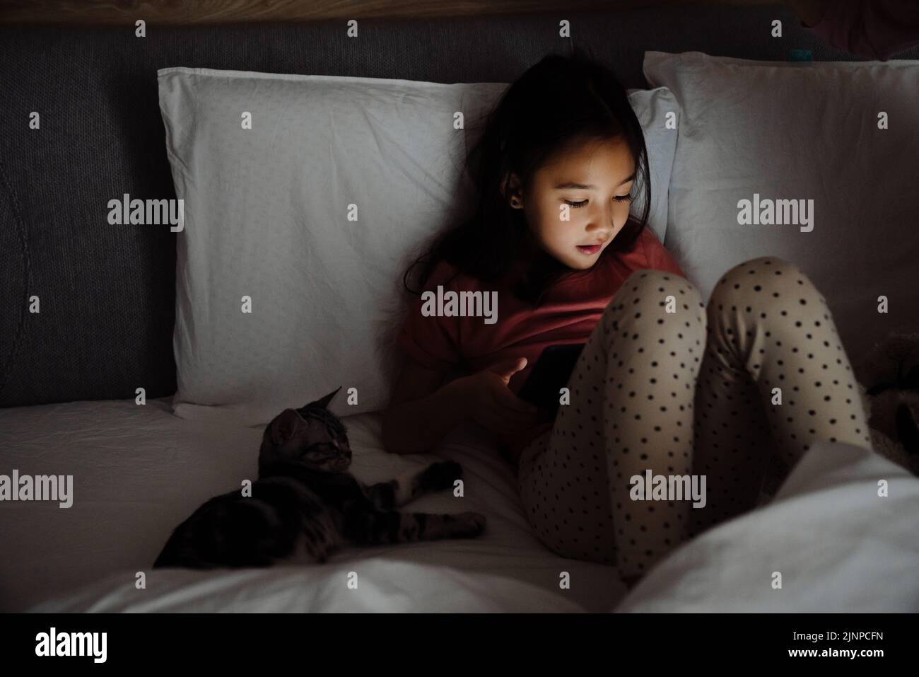 Asian girl using tablet computer while sitting on bed at home Stock ...