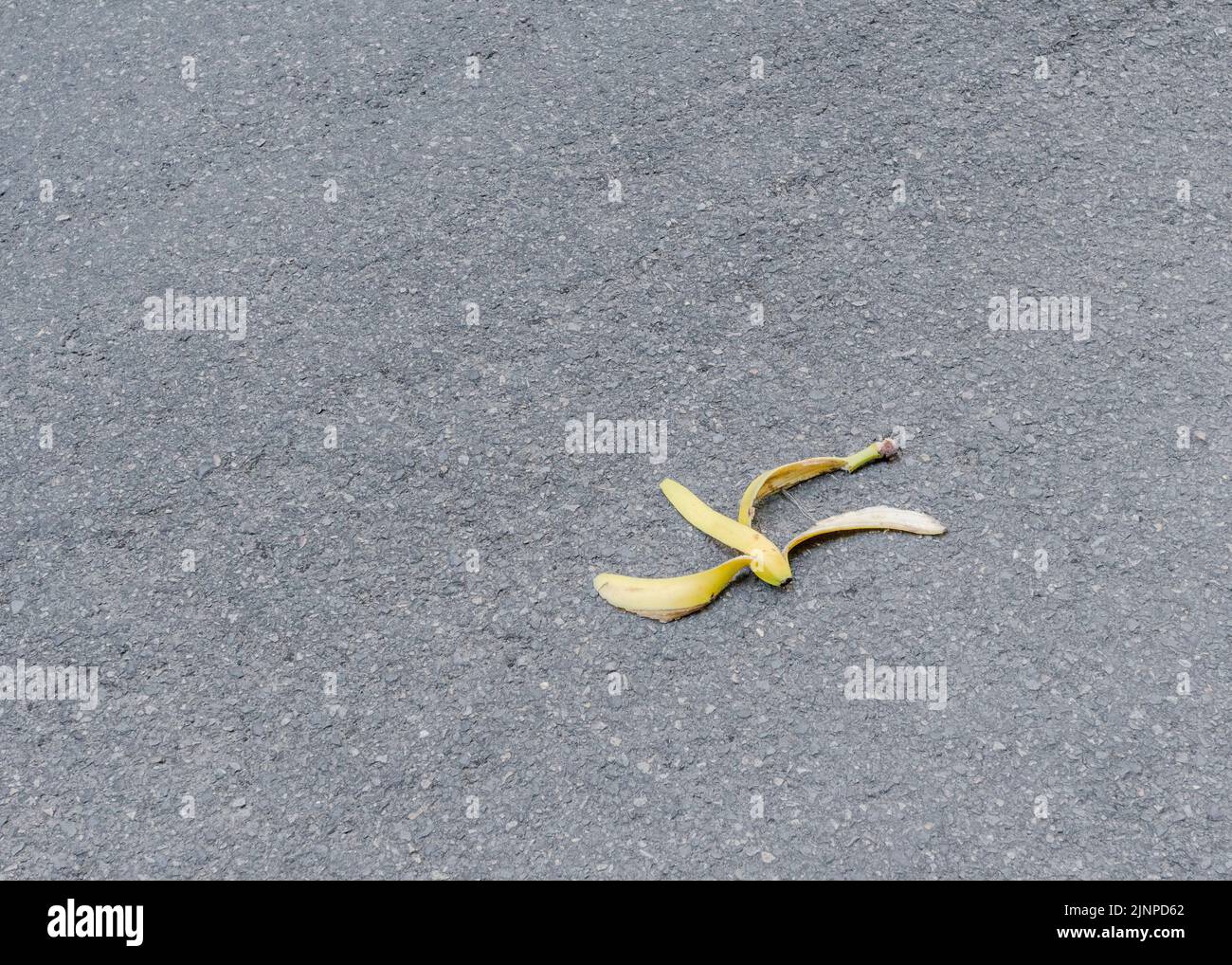 Discarded yellow banana skin / banana peel thrown onto tarmac country
