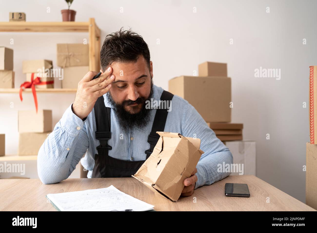 indian male courier showing damaged box, cheap parcel delivery, poor shipment quality. Small business parcel for shipment. Stock Photo