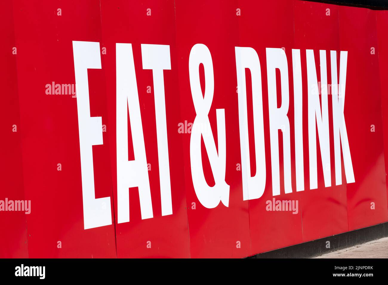 Angled view of large EAT and DRINK billboard sign, with white lettering
