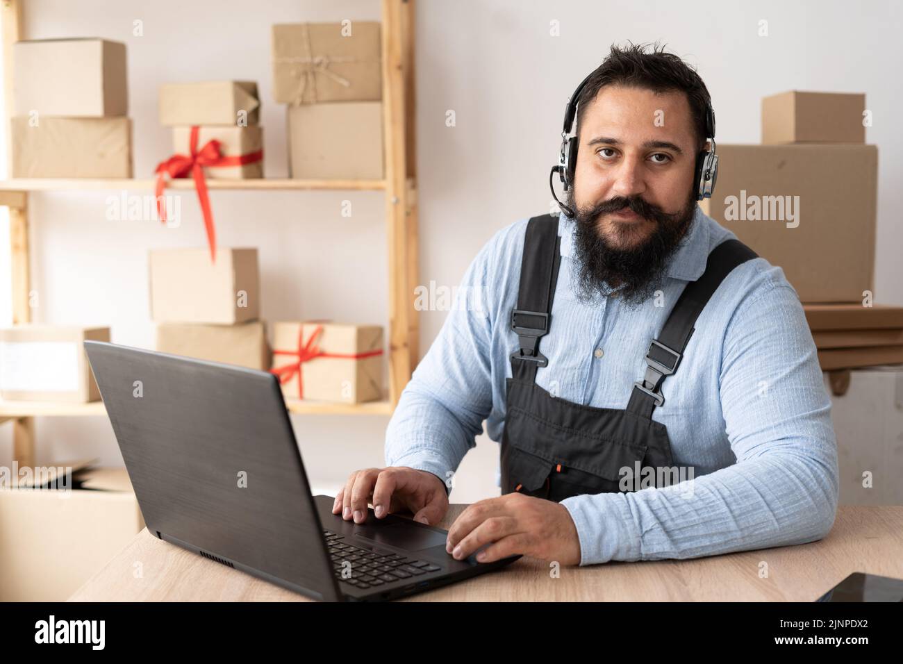 Starting small business entrepreneur taking online order using laptop and headphones while sitting at home office, dropshipping and goods delivery Stock Photo