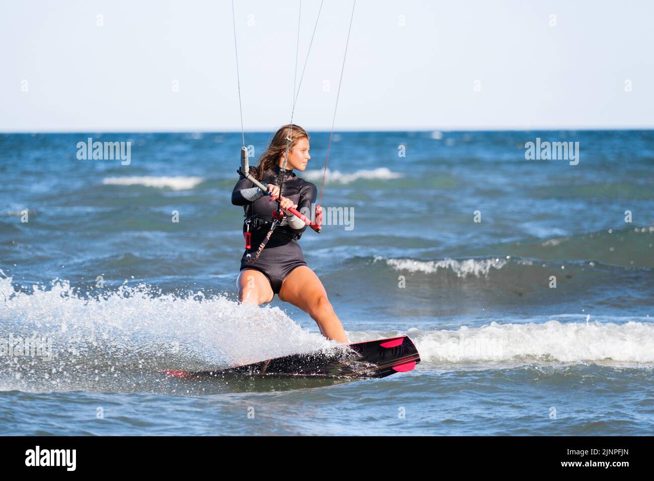 Kite surfing girl in swimsuit with kite in the sky rides the waves with