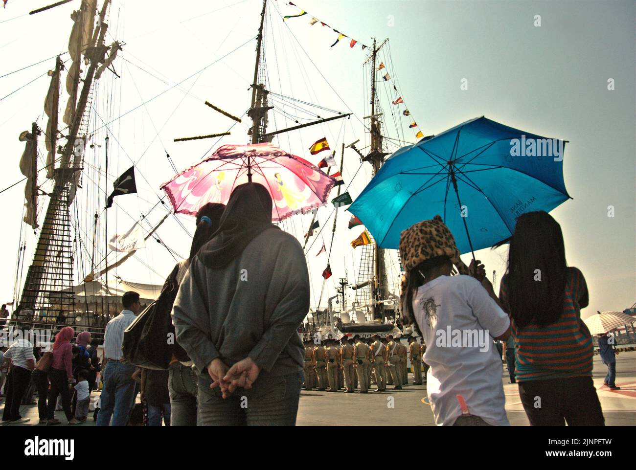 Visitors paying attention to Indonesian navy cadets who are lining up for a ceremony, in a background of KRI Dewaruci (Dewa Ruci), an Indonesian tall ship, that is being opened for public visitors at Kolinlamil harbour (Navy harbour) in Tanjung Priok, North Jakarta, Jakarta, Indonesia. Stock Photo