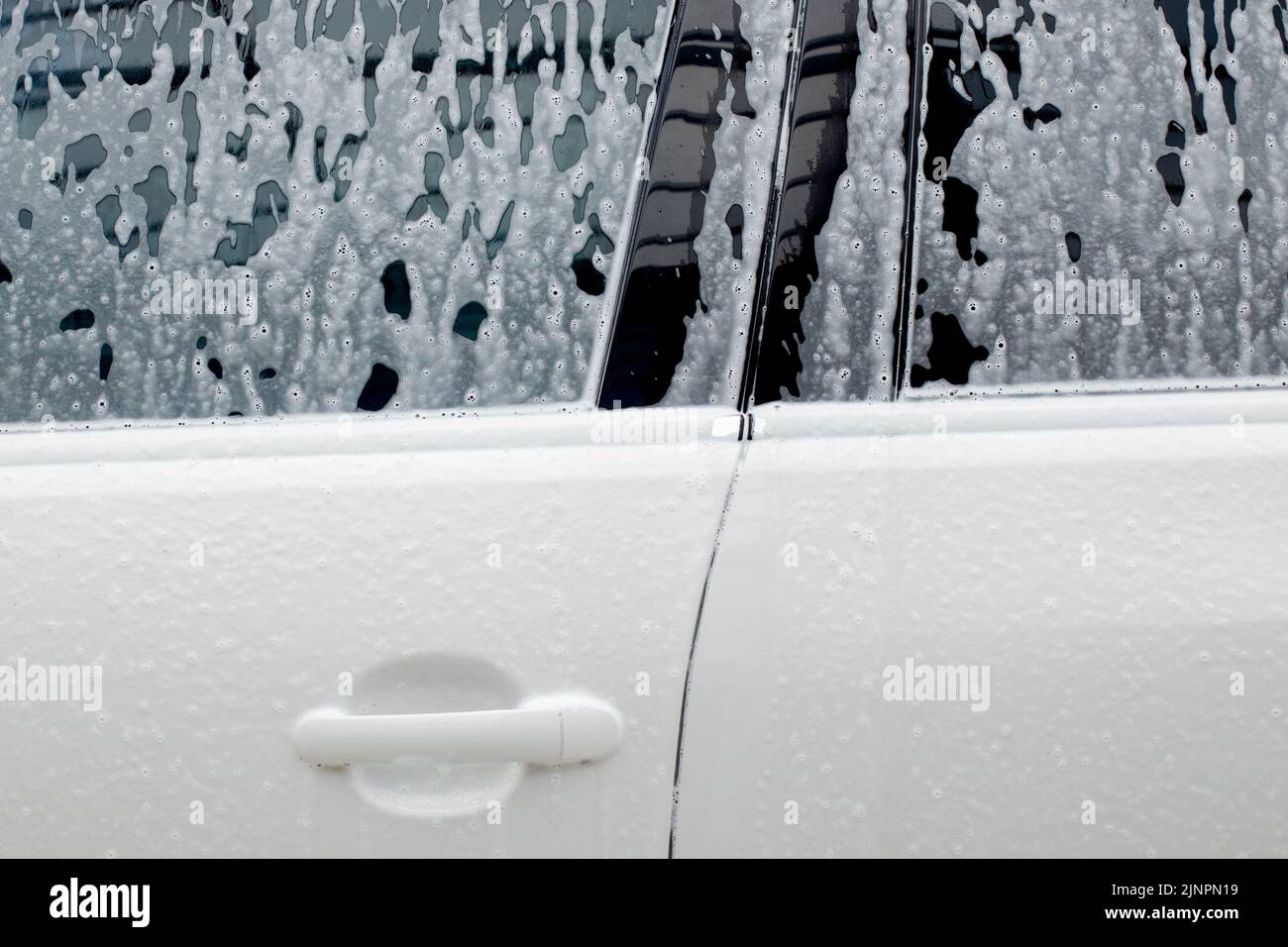 Washing mirrors in a white car with active foam. Car wash Stock Photo Alamy