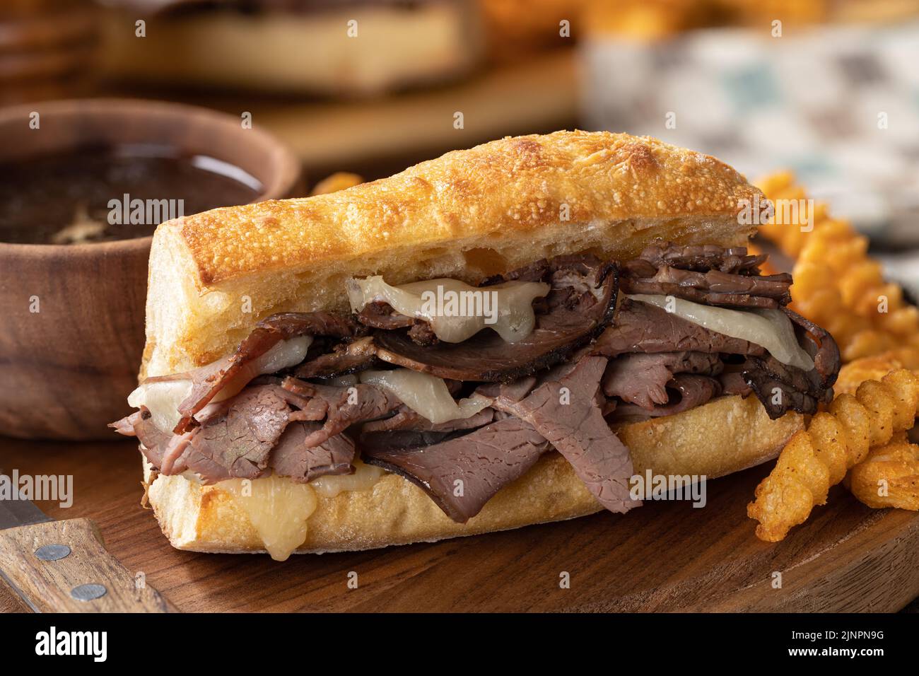 French dip sandwich and french fries with bowl of au jus in background