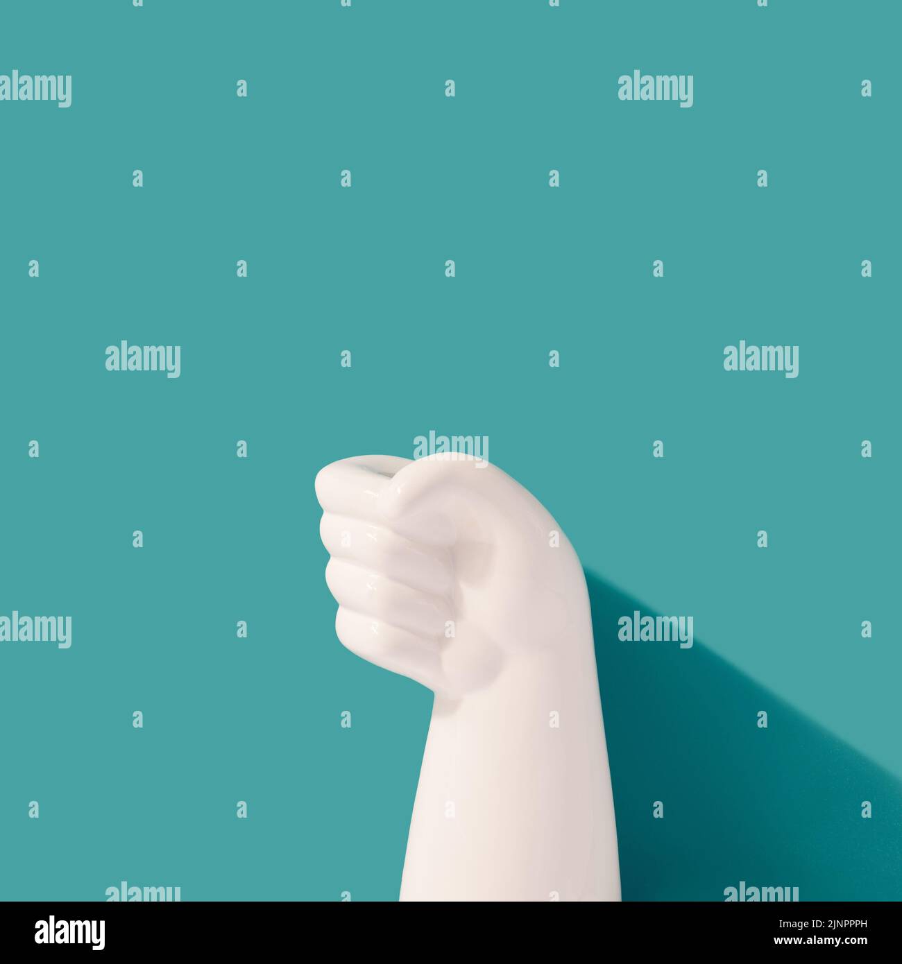 White plastic fist against the teal background. Gift, present minimal concept. Stock Photo
